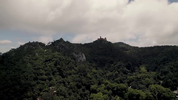 Sintra's Natural Park with distant hilltop Pena Palace against cloudy sky alt