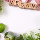 Girls Put Forward Inscription Vegan With Their Hands, Assembled From Wooden Cubes. Green Vegan