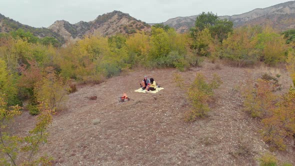 Romantic Couple Chats Happily By The Fire Surounded By Nature  alt