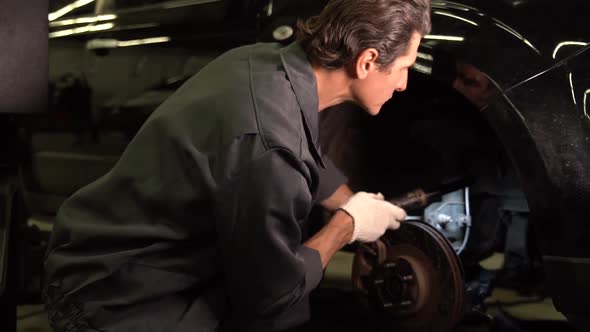Waist up portrait view of the auto mechanic man with lamp working at the workshop alt