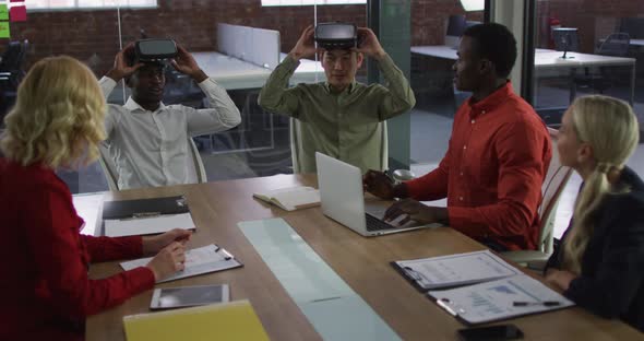 Diverse group of business colleagues sitting in meeting room using vr headset applauding alt