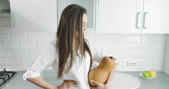 Woman Holding Pumpkin in Kitchen Portrait