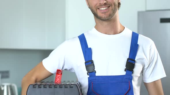 Friendly smiling workman holding box with tools and smiling to camera alt