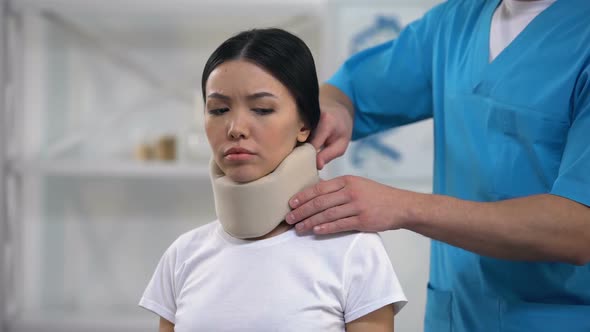 Male Orthopedist Fixing Sad Female Patient Foam Cervical Collar After Trauma alt