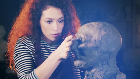 Lady Artist is Molding Facial Features on a Clay Sculpture alt