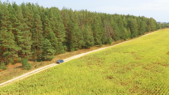 Elevated Aerial View Of Blue Car Vehicle Automobile In Fast Drive Motion On Countryside Country Road alt