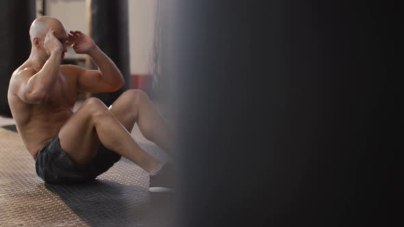 Caucasian muscular shirtless bald man exercising, doing sit ups alt