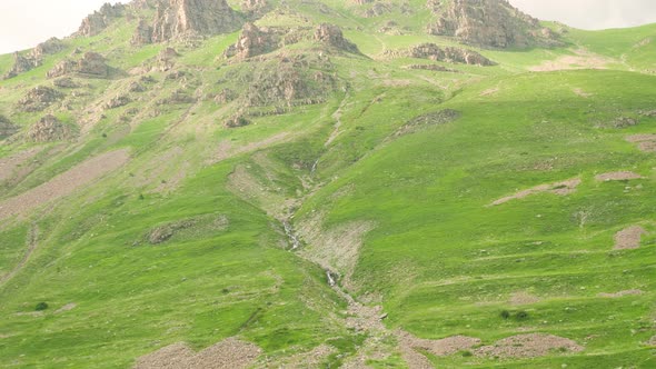 Looking up at the tall rocky hills covered in grass in Barcelonnette, France. alt