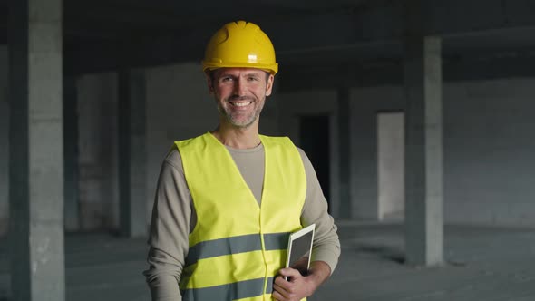 Portrait of caucasian engineer holding digital tablet while standing on construction site. alt