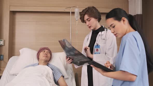 Female doctor explains x-ray film to patient at inpatient room bed in hospital. alt
