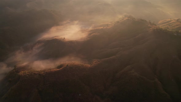 4K Aerial view from drone over mountains fog. Golden scenery at sunrise alt