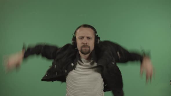 Young Handsome Man with Headphones Dancing on the Background of a Green Screen