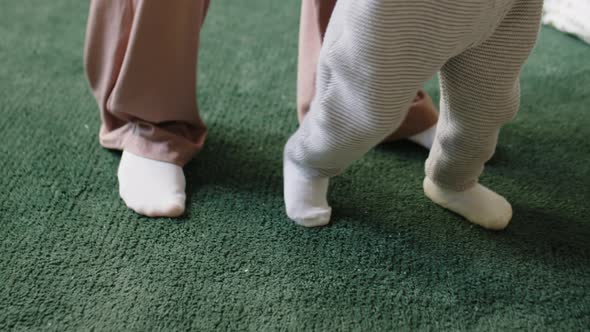 Baby Making First Steps with Help of Mom alt