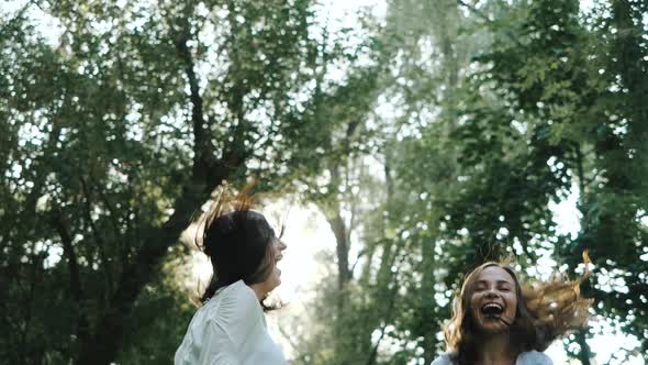 Close-up View of a Pair of Lovely Young Women Who Have a Photo Shoot on a Spring Day. Two Happy alt