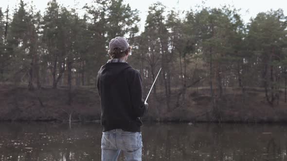 A young guy catches a predatory fish on spinning from the shore. Fishing as a hobby. alt