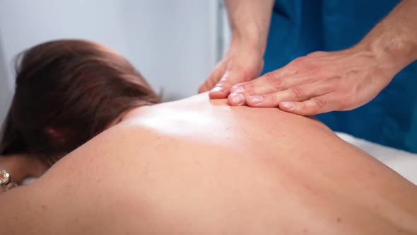 Male Professional Masseur Makes a Massage to a Slim Girl Client in a Spa Salon alt
