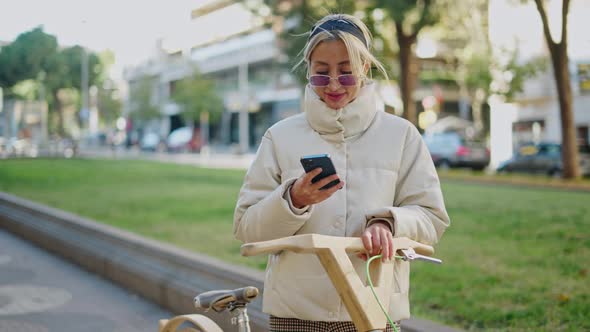 Female Cyclist Using Smartphone in Park alt