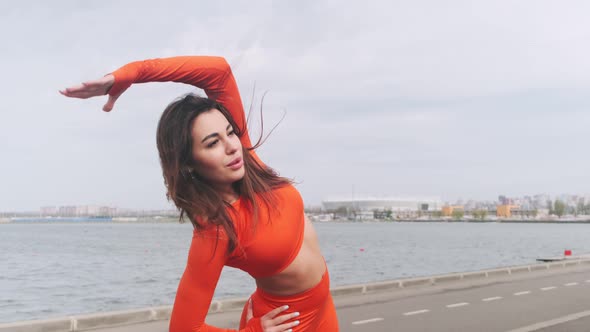 Young, beautiful athletic woman stretching her body, warming up before an outdoor workout. Girl in s alt