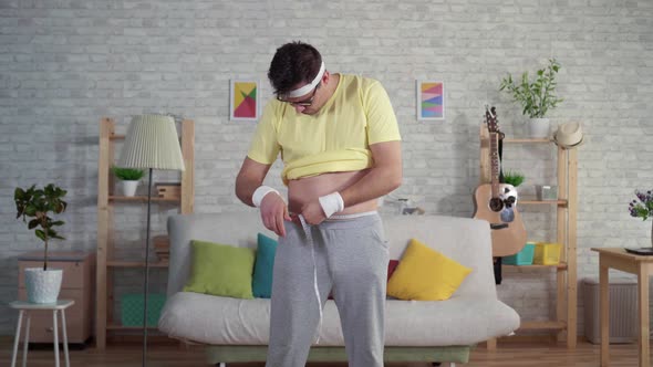Expressive Funny Man in Sportswear Uses Measuring Tape alt