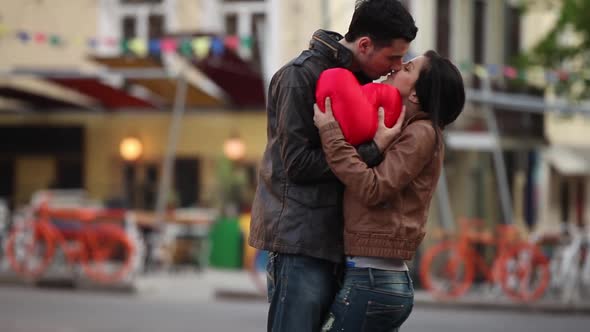 young couple with a heart kissing in the street