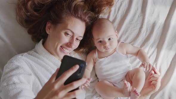 Close Up of Mother and Her Newborn Baby Making a Selfie or Video Call To Father or Relatives in a alt