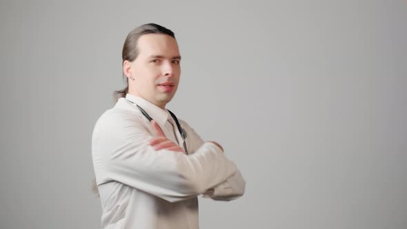 A Young Handsome Male Doctor with Long Hair Smiles and Looks at the Camera