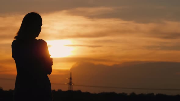 The Lone Silhouette of a Woman at Sunset Staring Into the Distance alt