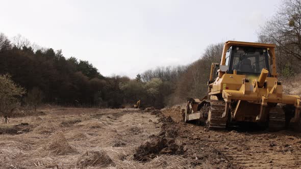 Bulldozer at Construction Site Shovels Soil Into a Heap alt