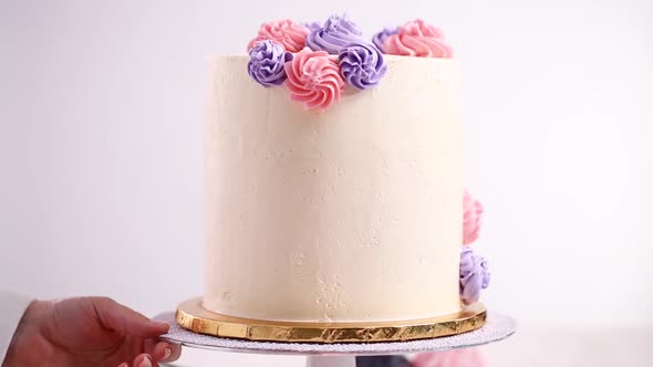 Time lapse. Flat lay. Piping pastel color buttercream rosettes on a white cake to make a unicorn cak alt