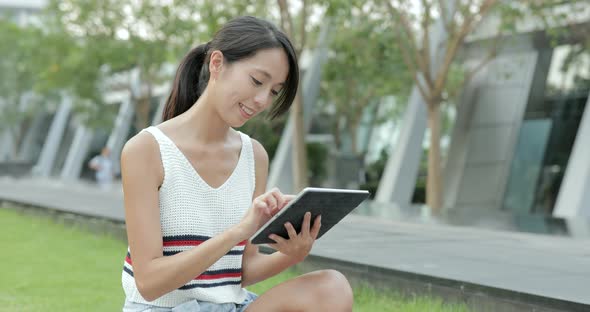 Woman using digital tablet at outdoor park alt