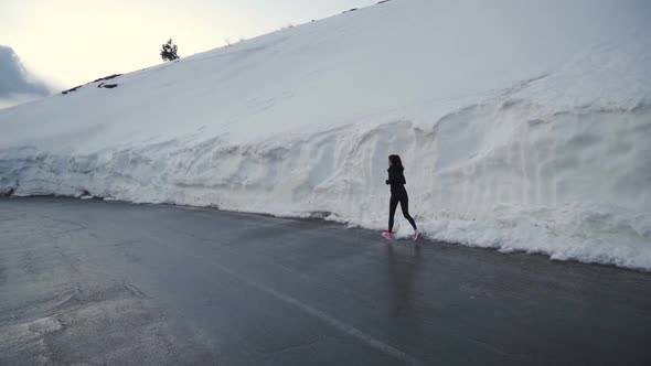 Confident Woman in Jogging Pants Running in Snow Corridor in the Mountains in Bulgaria alt