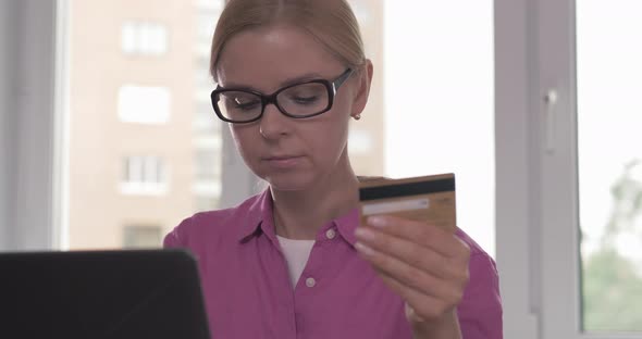 Portrait of Smiling Woman Holding Credit Card in Her Hand While Shopping Online