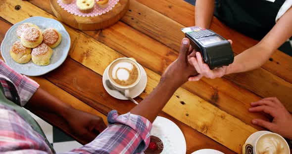 Customer making payment through payment terminal machine at counter