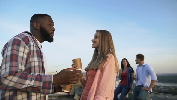 Multiracial Couple Laughing and Flirting at Roof, Spending Time With Friends