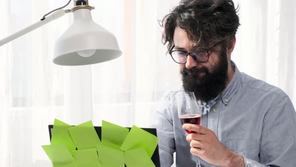 Man Types and Enhoy a Glass of Wine and Looks Happily at the Computer Screen alt