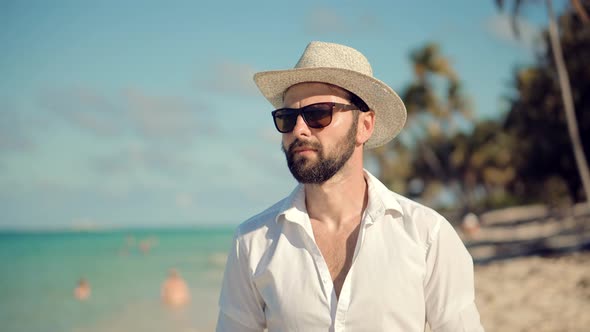 Man Walking On Tropical Beach. Guy Relaxing On Caribbean Beach. Tanned Man In Hat Healthy Skin. alt