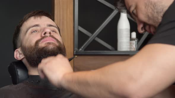 Barber Trimming Beard of Client