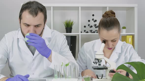 Two Young Researchers in Lab Discussing Results of Research in Biotechnology