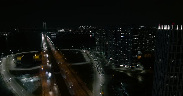 City Street at Night. Light Trails from Moving Cars on the Dusk Urban Road with Modern Buildings alt
