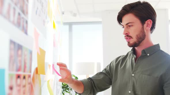 Executive reading sticky notes on glass wall alt