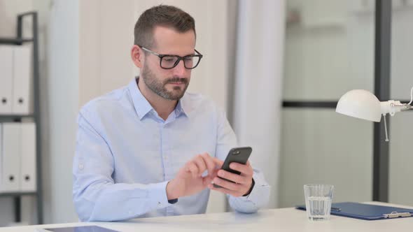 Middle Aged Man Excited By Success on Smartphone at Work alt
