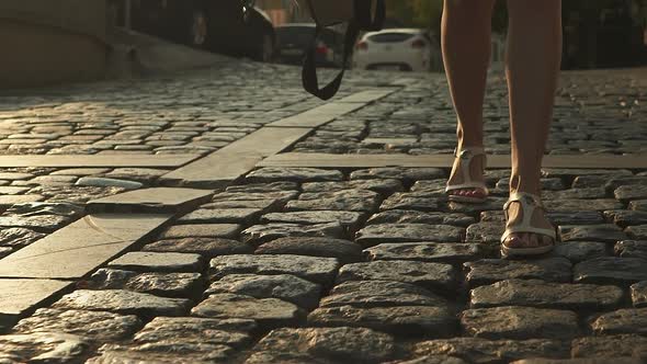 Slow Motion Detail of Woman's Feet Walking Through City on Pavement From Behind