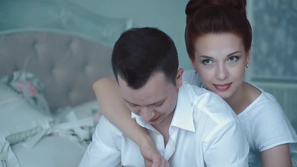 Young Beautiful Couple Sitting in the Morning on the Bed, Looking Out the Window, Basking, Close-up alt