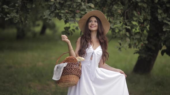 Young Beautiful Woman with White Teeth, a Beautiful Smile in a Straw Hat Holds a Food Basket and