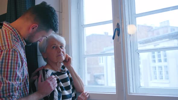 Caucasian Man Supporting His Upset Mother in Her 60s alt