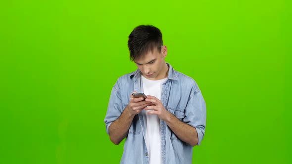 Man Looks at the Phone in the Photo, and Has Fun. Green Screen alt