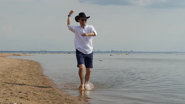 Happy Adult Man in Cowboy Hat Walking Along the Seashore