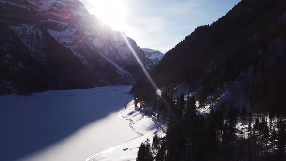 Aerial view over a wonderful valley with a frozen lake and two big snowy mountains in Klöntal Switze alt
