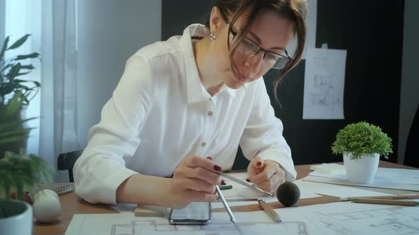 Young pretty engineer, architect or designer woman works with drawings in office