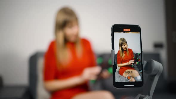 Young Woman in Red Dress Recording Video About FPV Drone alt